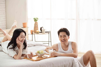 快乐的年轻情侣在床上吃早餐漂亮的高质量素材