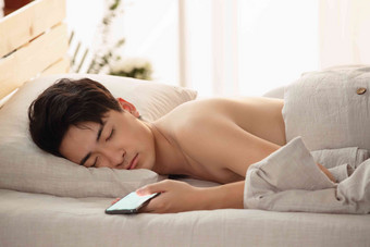 玩手机玩到睡着的年轻男人享乐清晰摄影图