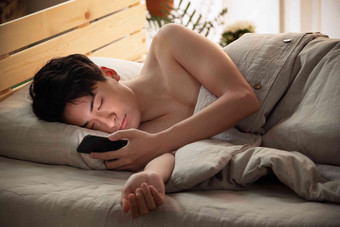 躺在床上玩手机的年轻男人仅男人氛围相片