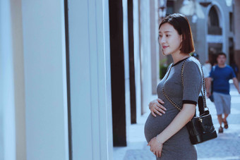 孕妇站在商店橱窗前放松氛围摄影