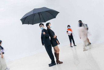 拿着雨伞的<strong>商务</strong>男女戴着口罩站在人群中