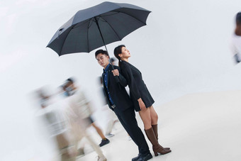 拿着雨伞的<strong>商务</strong>男女站在人群中