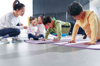 东方儿童在教练的指导下进行体能训练瑜伽垫写实摄影