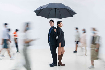 拿着雨伞的商务男女站在人群中