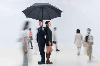 拿着雨伞的商务男女站在人群中