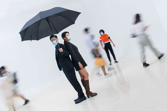拿着雨伞的<strong>商务</strong>男女戴着口罩站在人群中