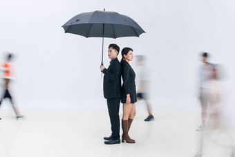 拿着<strong>雨伞</strong>的商务男女站在人群中