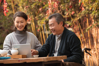 老年夫妇在庭院内使用平板电脑露齿一笑高质量<strong>照片</strong>