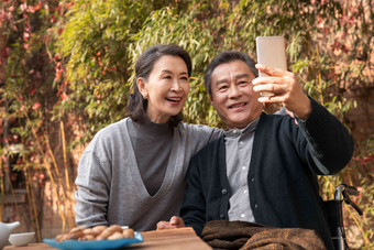 老年夫妇在庭院使用手机自拍