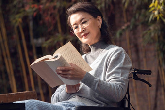 <strong>户外</strong>老年女人坐在轮椅上看书