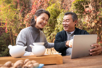 老年夫妇在庭院内使用平板电脑放松氛围拍摄