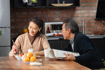 老年夫妇在家中享用早餐报纸氛围摄影图