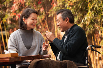 快乐的老年夫妇在庭院内品茶休闲高质量镜头