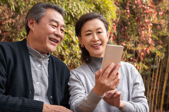 老年夫妇在庭院使用手机竹子高质量摄影图