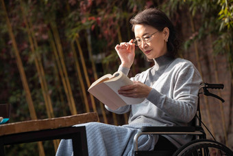 户外老年女人坐在轮椅上看书