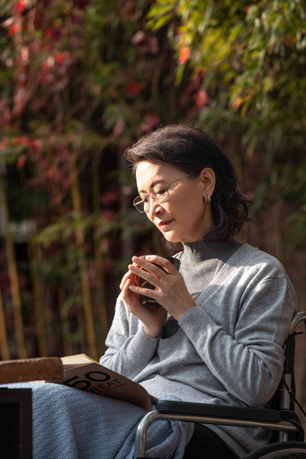 户外老年女人坐在轮椅上看书女人高质量影相