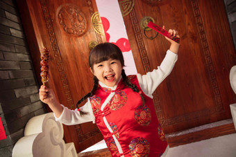 手举糖葫芦红包的快乐小女孩房屋高端照片