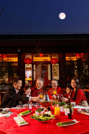 东方家庭在中式庭院内干杯庆祝新年年夜饭图片