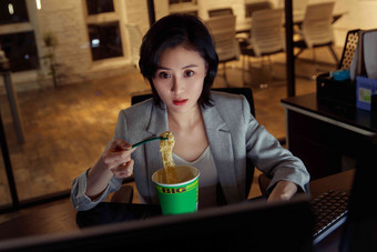 在办公室加班吃方便面的青年女人压力清晰摄影