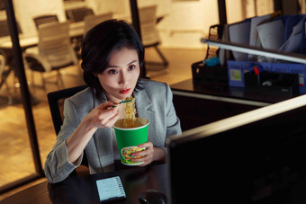 在办公室加班吃方便面的青年女人吃氛围照片