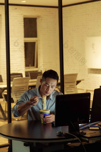 在办公室加班吃<strong>方便面</strong>的青年男人中国写实照片
