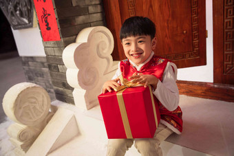 可爱的小男孩抱着礼品盒坐着高清摄影