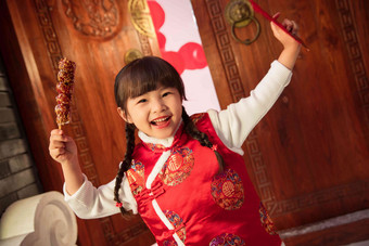 手举糖葫芦红包的快乐小女孩东方人照片