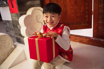 可爱的小男孩抱着礼品盒露齿一笑高质量摄影