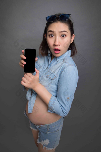 穿着时尚的孕妇拿着手机<strong>预期</strong>高质量相片