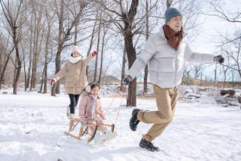 在雪地上玩雪橇的一家人中年男人影相