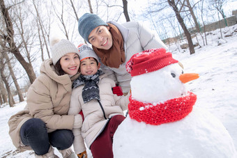 一家三口在雪地里<strong>堆雪人</strong>