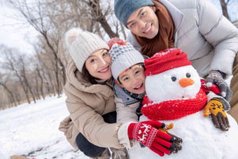 一家三口在雪地里堆雪人水平构图氛围场景