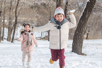 两个小朋友在雪地里玩耍奔跑写实摄影图