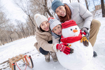 一家三口在雪地里<strong>堆雪人</strong>