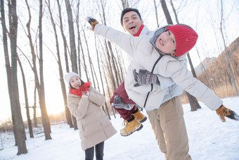 在雪地上玩耍的一家三口中年人写实照片