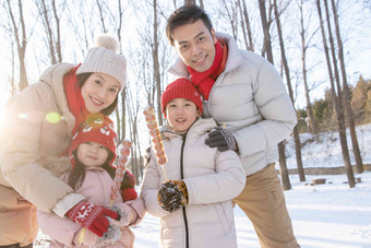 雪地里拿着糖葫芦的快乐家庭女儿高端相片
