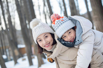 年轻妈妈带着孩子在雪地玩耍手套写实拍摄
