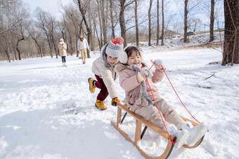 欢乐家庭在雪地上玩雪橇白昼高清素材