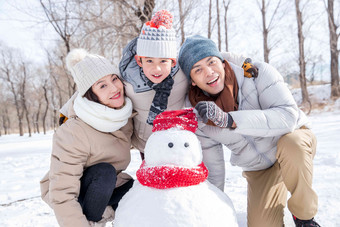 一家三口在雪地里堆雪人户外高端摄影