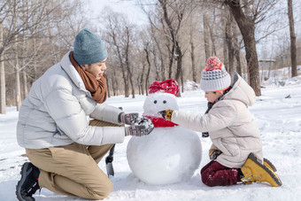 爸爸和孩子推雪人独生子家庭氛围照片