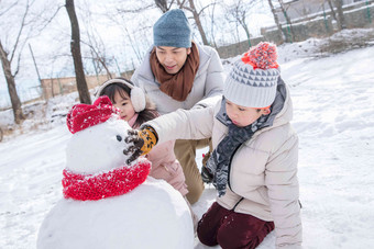 爸爸和孩子们推雪人水平构图写实场景