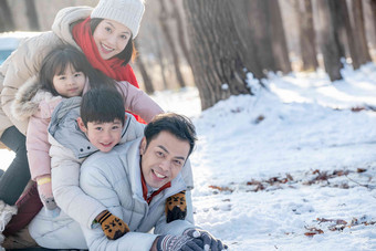 趴在雪地里玩耍的快乐家庭