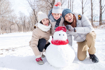 一家三口在雪地里<strong>堆雪人</strong>