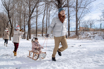 欢乐家庭在雪地上玩雪橇男人写实相片