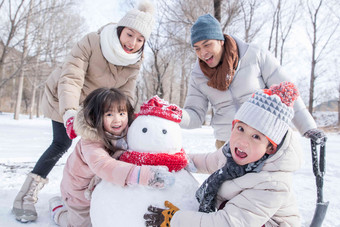 欢乐家庭在雪地里<strong>堆雪人</strong>雪地高端照片