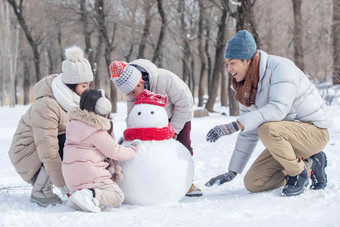 欢乐家庭在雪地里堆雪人水平构图高清镜头