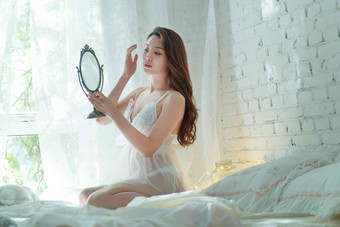 漂亮<strong>的</strong>青年女人坐在床上照镜子坐着高质量照片
