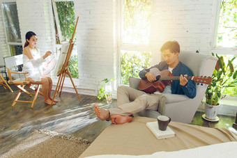 快乐的青年伴侣在家弹吉他画画画笔高质量素材