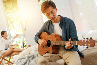 青年男人在家弹吉他床高清摄影