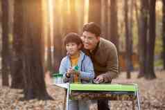 户外树林里父亲和儿子烧烤户外氛围场景
